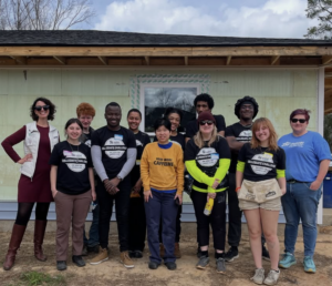 UMW team poses with a new homeowner and Habitat for Humanity representatives in front of the house they helped build. (L-R: Habitat for Humanity Guest Speaker, Veda Salazar, Ian Frazier, Aloysious Kabonge, Chloe Jones, Paris Jones, the new homeowner, Walter Parks, Lindsey Coates-Crawford, Alton Guinn, Faye McKenzie, and Habitat Volunteer Coordinator April Elswick).